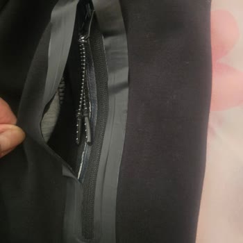 Nike Tech Eşofmanda Rozet Soyulması Ve Fermuarlı Aksesuar Yırtılması